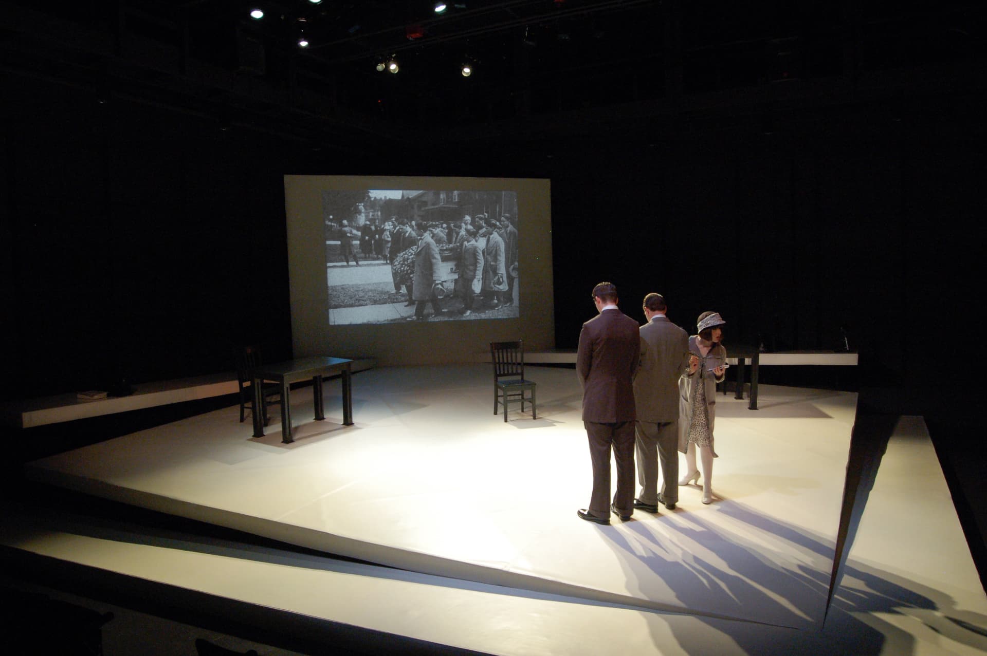Never The Sinner — Frank's funeral archival image projected behind the reporters