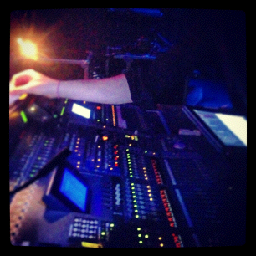 Medea — hands on the FOH console mid-show in stage light